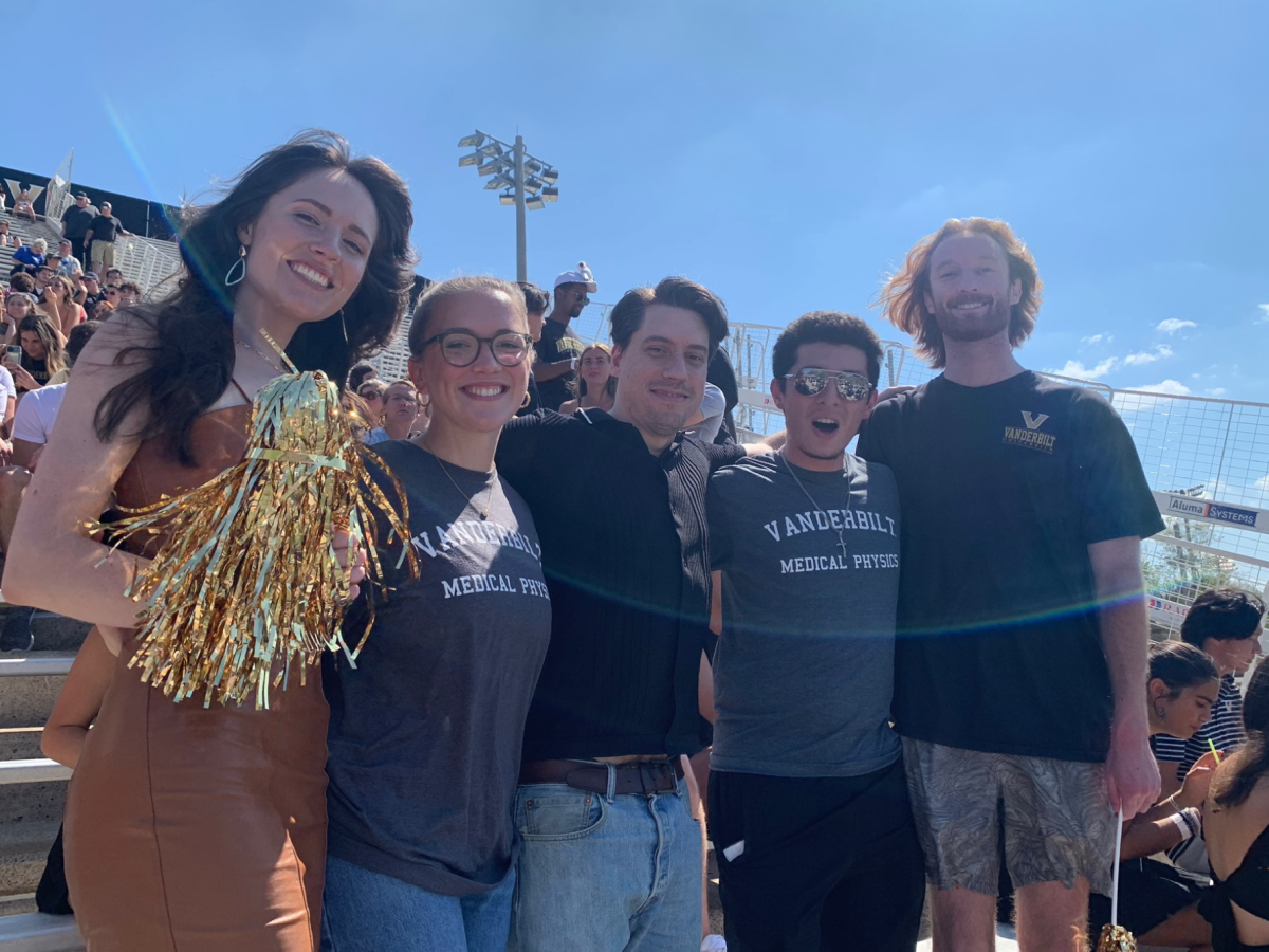 Five Vanderbilt MSMP students smile and hold pom poms at a football game