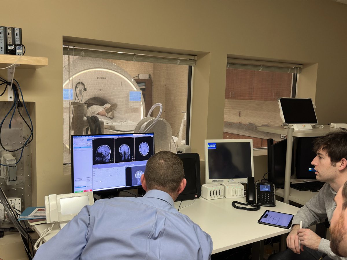 Vanderbilt clinicians and MIS students examine brain scans while patient lies on a table entering an MRI machine.